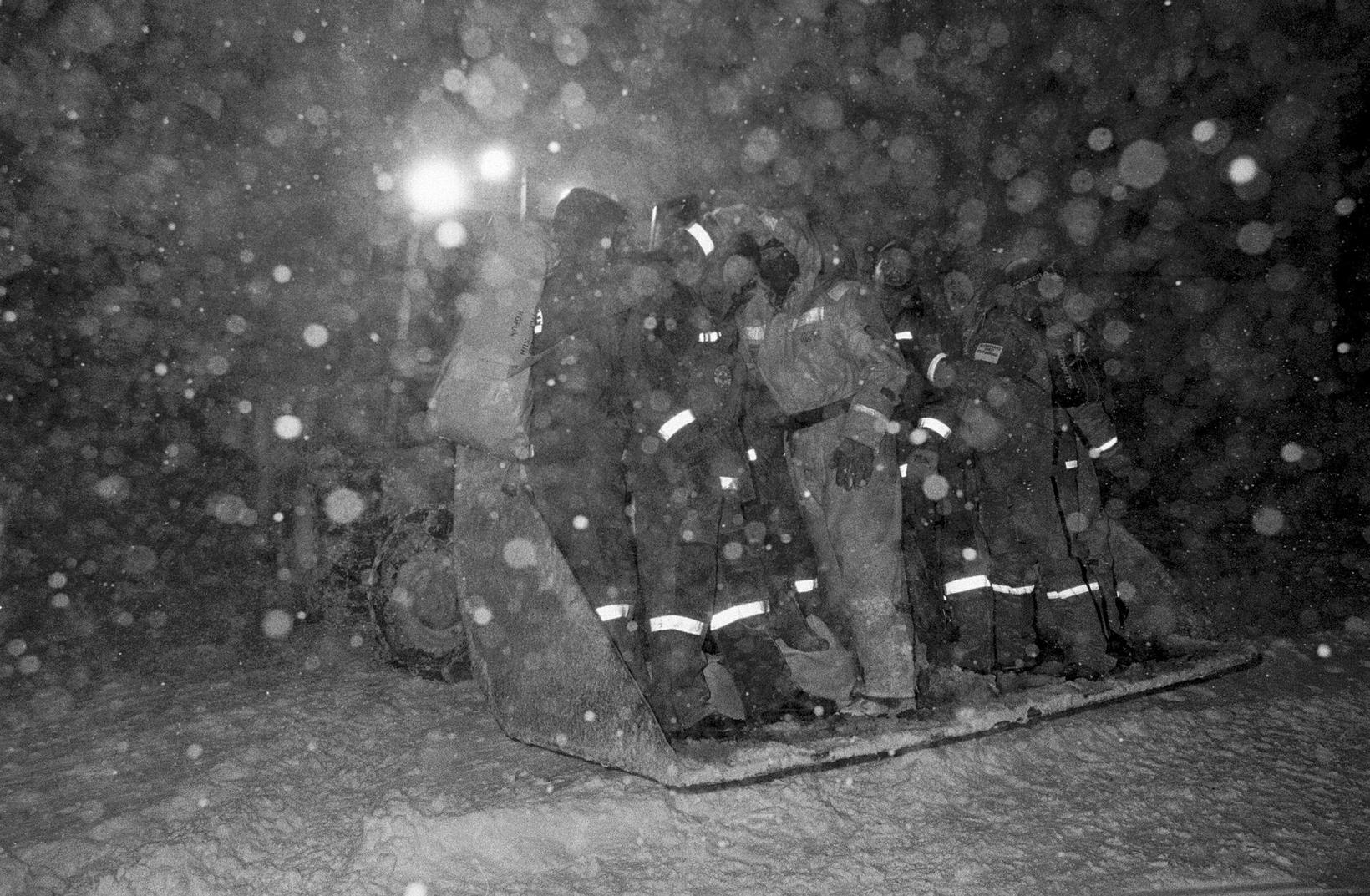 Les sauveteurs s'accroupissent dans une pelle alors qu'ils se dirigent vers le…